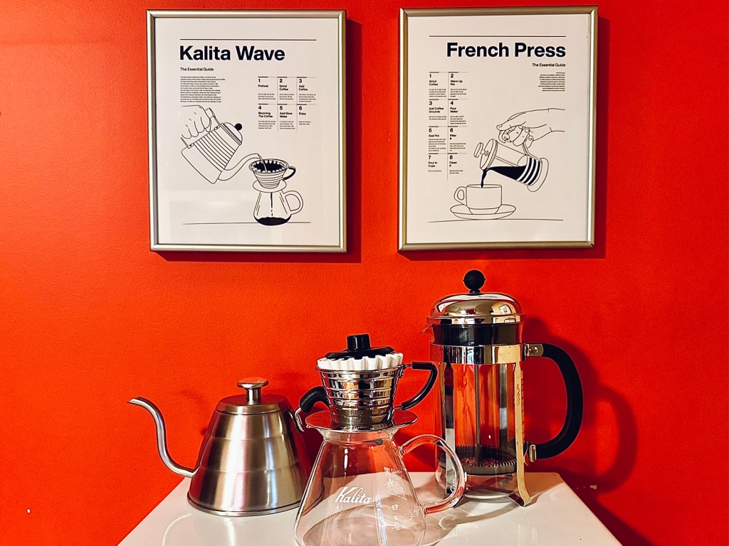 Kalita Wave pour over coffee maker and classic French press coffee maker pictured in front of 2 frames on the wall with directions on how to use each coffee maker option.